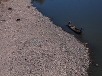 Kashmiri fishermen catch fish as stray dogs search for food on the dried portion of the river as a dry spell reduces the water level of the...