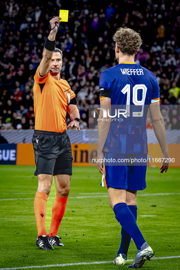 Referee Slavko Vincic gives Netherlands midfielder Mats Wieffer a yellow card during the match between Germany and the Netherlands at the Al...