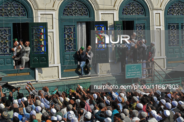 People pray as the head cleric (not in picture) displays the holy relic during the festival of Sufi Saint Sheikh Abdul Qadir Jeelani (RA) in...