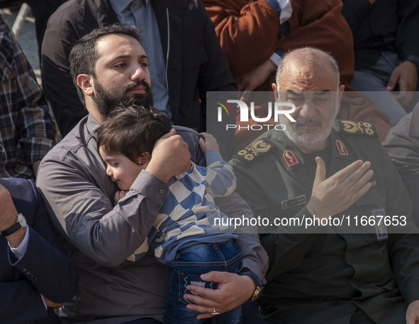 Hossein Salami, commander-in-chief of the Islamic Revolutionary Guard Corps (IRGC), beats himself while sitting next to a son of a commander...