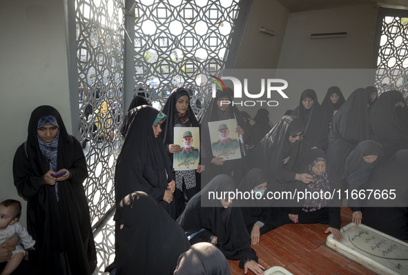 Two veiled Iranian mourners hold portraits of a commander of the Islamic Revolutionary Guard Corps' (IRGC) Quds Force, Abbas Nilforoushan, w...