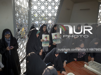 Two veiled Iranian mourners hold portraits of a commander of the Islamic Revolutionary Guard Corps' (IRGC) Quds Force, Abbas Nilforoushan, w...