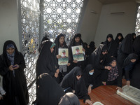 Two veiled Iranian mourners hold portraits of a commander of the Islamic Revolutionary Guard Corps' (IRGC) Quds Force, Abbas Nilforoushan, w...