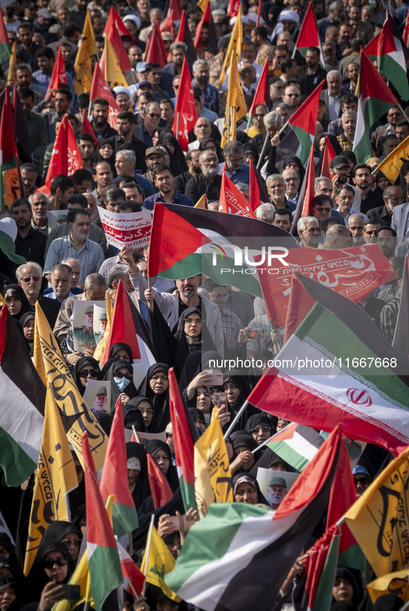 Iranian mourners wave a Palestinian flag and an Iranian flag while taking part in a funeral for a commander of the Islamic Revolutionary Gua...