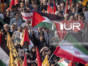 Iranian mourners wave a Palestinian flag and an Iranian flag while taking part in a funeral for a commander of the Islamic Revolutionary Gua...