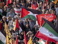 Iranian mourners wave a Palestinian flag and an Iranian flag while taking part in a funeral for a commander of the Islamic Revolutionary Gua...