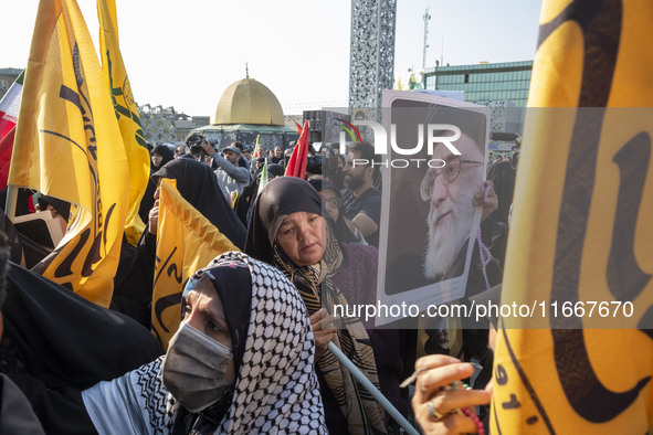 A veiled Iranian mourner holds a portrait of Iran's Supreme Leader, Ayatollah Ali Khamenei, while taking part in a funeral for a commander o...