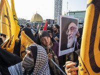 A veiled Iranian mourner holds a portrait of Iran's Supreme Leader, Ayatollah Ali Khamenei, while taking part in a funeral for a commander o...