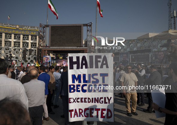 An elderly Iranian man holds an anti-Israeli placard while taking part in a funeral for a commander of the Islamic Revolutionary Guard Corps...