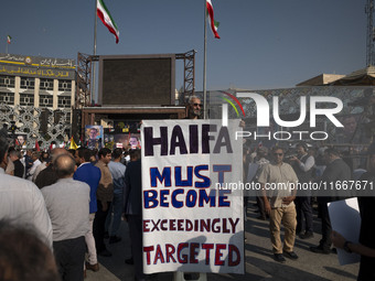 An elderly Iranian man holds an anti-Israeli placard while taking part in a funeral for a commander of the Islamic Revolutionary Guard Corps...