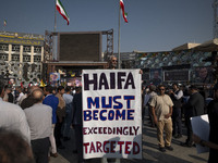 An elderly Iranian man holds an anti-Israeli placard while taking part in a funeral for a commander of the Islamic Revolutionary Guard Corps...