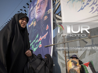 A veiled Iranian mourner holds a Palestinian flag and a portrait of Lebanon's Hezbollah leader, Hassan Nasrallah, while a veiled woman walks...