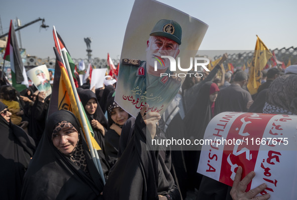 Iranian mourners hold an anti-U.S. placard and a portrait of a commander of the Islamic Revolutionary Guard Corps' (IRGC) Quds Force, Abbas...