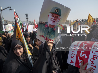 Iranian mourners hold an anti-U.S. placard and a portrait of a commander of the Islamic Revolutionary Guard Corps' (IRGC) Quds Force, Abbas...