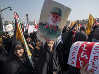 Iranian mourners hold an anti-U.S. placard and a portrait of a commander of the Islamic Revolutionary Guard Corps' (IRGC) Quds Force, Abbas...