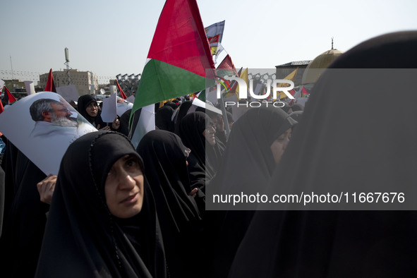 Veiled Iranian mourners carry a Palestinian flag and a portrait of Lebanon's Hezbollah leader, Hassan Nasrallah, while participating in a fu...