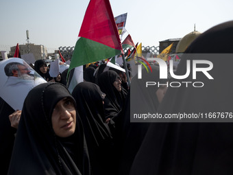 Veiled Iranian mourners carry a Palestinian flag and a portrait of Lebanon's Hezbollah leader, Hassan Nasrallah, while participating in a fu...