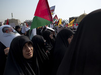 Veiled Iranian mourners carry a Palestinian flag and a portrait of Lebanon's Hezbollah leader, Hassan Nasrallah, while participating in a fu...