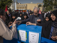 Iranian mourners place bank receipts into charity boxes meant to help the people of Lebanon, Gaza, and Yemen after participating in the fune...