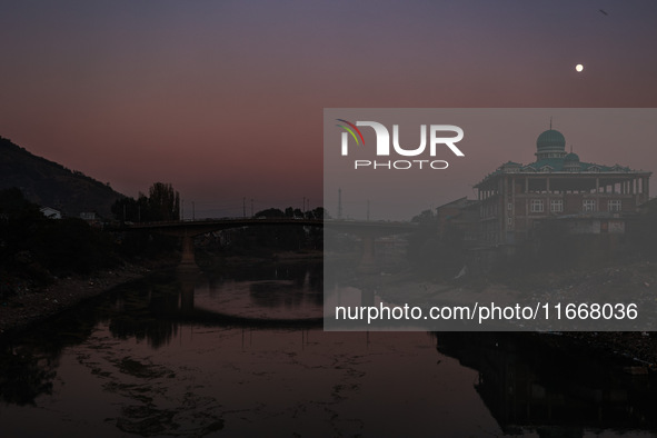 The moon appears over a mosque in Baramulla, Jammu and Kashmir, India, on October 15, 2024. 