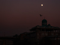 The moon appears over a mosque in Baramulla, Jammu and Kashmir, India, on October 15, 2024. (