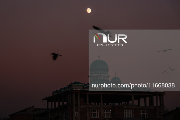 The moon appears over a mosque in Baramulla, Jammu and Kashmir, India, on October 15, 2024. 