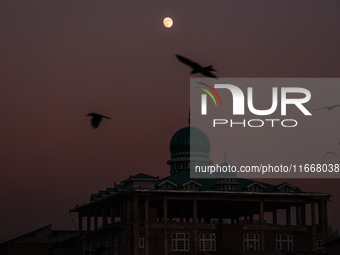 The moon appears over a mosque in Baramulla, Jammu and Kashmir, India, on October 15, 2024. (