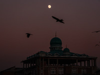 The moon appears over a mosque in Baramulla, Jammu and Kashmir, India, on October 15, 2024. (