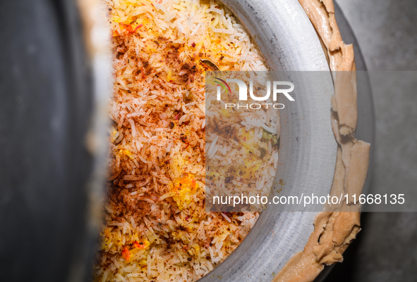 A pot of biryani, with aromatic basmati rice, cooked chicken, and a variety of spices such as saffron, kewra water, and fried onions known a...