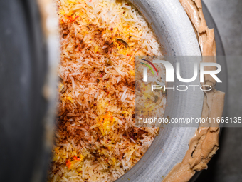 A pot of biryani, with aromatic basmati rice, cooked chicken, and a variety of spices such as saffron, kewra water, and fried onions known a...