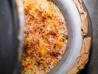 A pot of biryani, with aromatic basmati rice, cooked chicken, and a variety of spices such as saffron, kewra water, and fried onions known a...