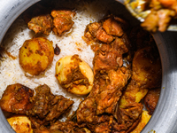 A pot of biryani, with aromatic basmati rice, cooked chicken, and a variety of spices such as saffron, kewra water, and fried onions known a...