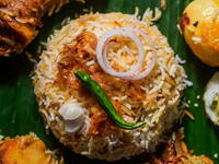 A pot of biryani, with aromatic basmati rice, cooked chicken, and a variety of spices such as saffron, kewra water, and fried onions known a...