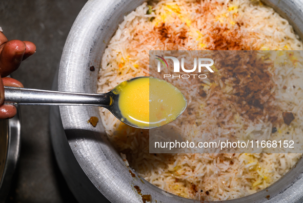 A pot of biryani, with aromatic basmati rice, cooked chicken, and a variety of spices such as saffron, kewra water, and fried onions known a...