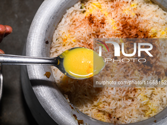 A pot of biryani, with aromatic basmati rice, cooked chicken, and a variety of spices such as saffron, kewra water, and fried onions known a...