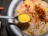 A pot of biryani, with aromatic basmati rice, cooked chicken, and a variety of spices such as saffron, kewra water, and fried onions known a...