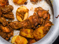 A pot of biryani, with aromatic basmati rice, cooked chicken, and a variety of spices such as saffron, kewra water, and fried onions known a...