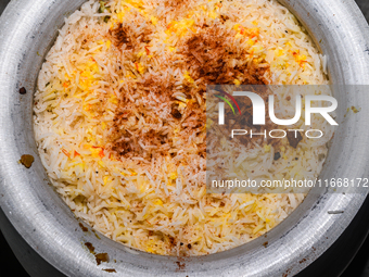 A pot of biryani, with aromatic basmati rice, cooked chicken, and a variety of spices such as saffron, kewra water, and fried onions known a...