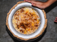 A pot of biryani, with aromatic basmati rice, cooked chicken, and a variety of spices such as saffron, kewra water, and fried onions known a...