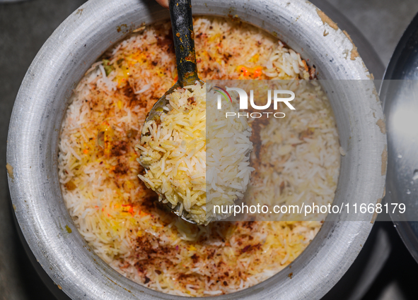 A pot of biryani, with aromatic basmati rice, cooked chicken, and a variety of spices such as saffron, kewra water, and fried onions known a...