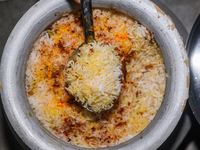 A pot of biryani, with aromatic basmati rice, cooked chicken, and a variety of spices such as saffron, kewra water, and fried onions known a...