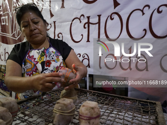 A woman manipulates molds to make chocolate skulls for sale in Mexico City, Mexico, on the eve of Day of the Dead. Sugar skulls are made fro...