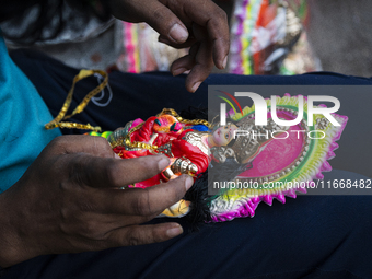 A person decorates an idol of Lakshmi for sale on the eve of the Lakshmi Puja festival in Guwahati, India, on October 15, 2024. Lakshmi is o...