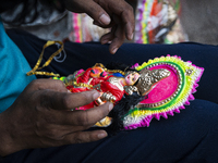 A person decorates an idol of Lakshmi for sale on the eve of the Lakshmi Puja festival in Guwahati, India, on October 15, 2024. Lakshmi is o...