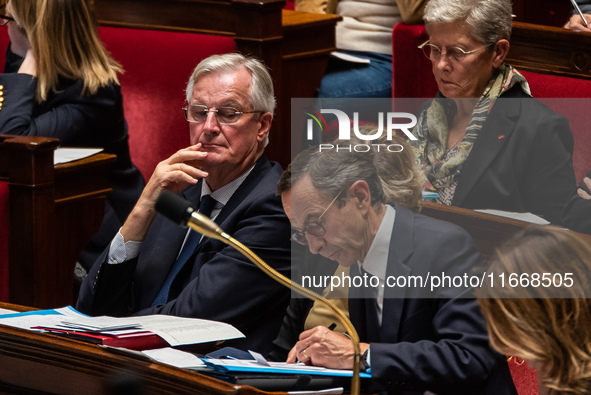 Prime Minister Michel Barnier looks at Interior Minister Bruno Retailleau's notes during question time in Parliament in Paris, France, on Oc...