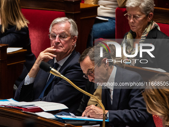 Prime Minister Michel Barnier looks at Interior Minister Bruno Retailleau's notes during question time in Parliament in Paris, France, on Oc...