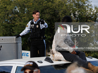 A U.S. Park Police officer speaks with an Indigenous demonstrator sitting atop a vehicle attached to a horse trailer near the U.S. Capitol i...