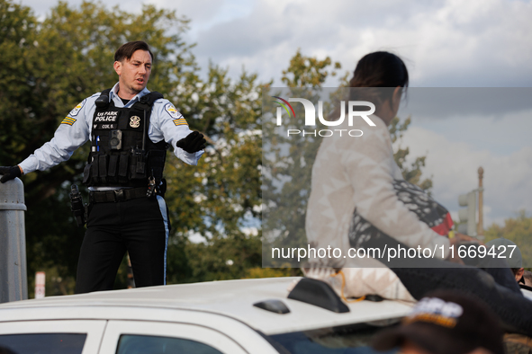 A U.S. Park Police officer speaks with an Indigenous demonstrator sitting atop a vehicle attached to a horse trailer near the U.S. Capitol i...