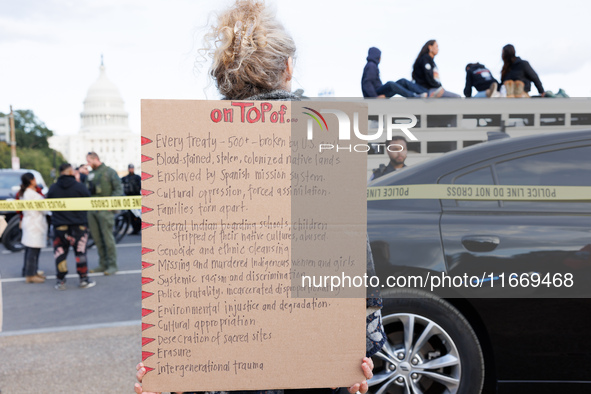 A woman wears a protest sign as police surround a horse trailer after Indigenous demonstrators clash with police near the U.S. Capitol in Wa...