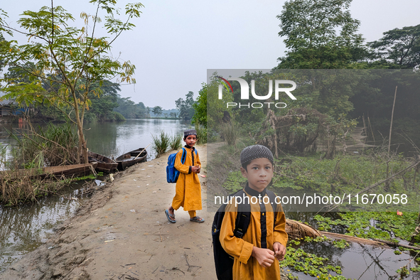 Children go to school in the early morning in a rural area in Feni, Bangladesh, on October 16, 2024. Many fish enclosures and ponds are wash...